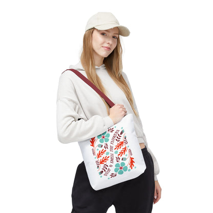 Woman in a white sweatshirt and cap holding the Stop and Smell The Flowers tote bag, showcasing its nature-inspired design and durable construction.