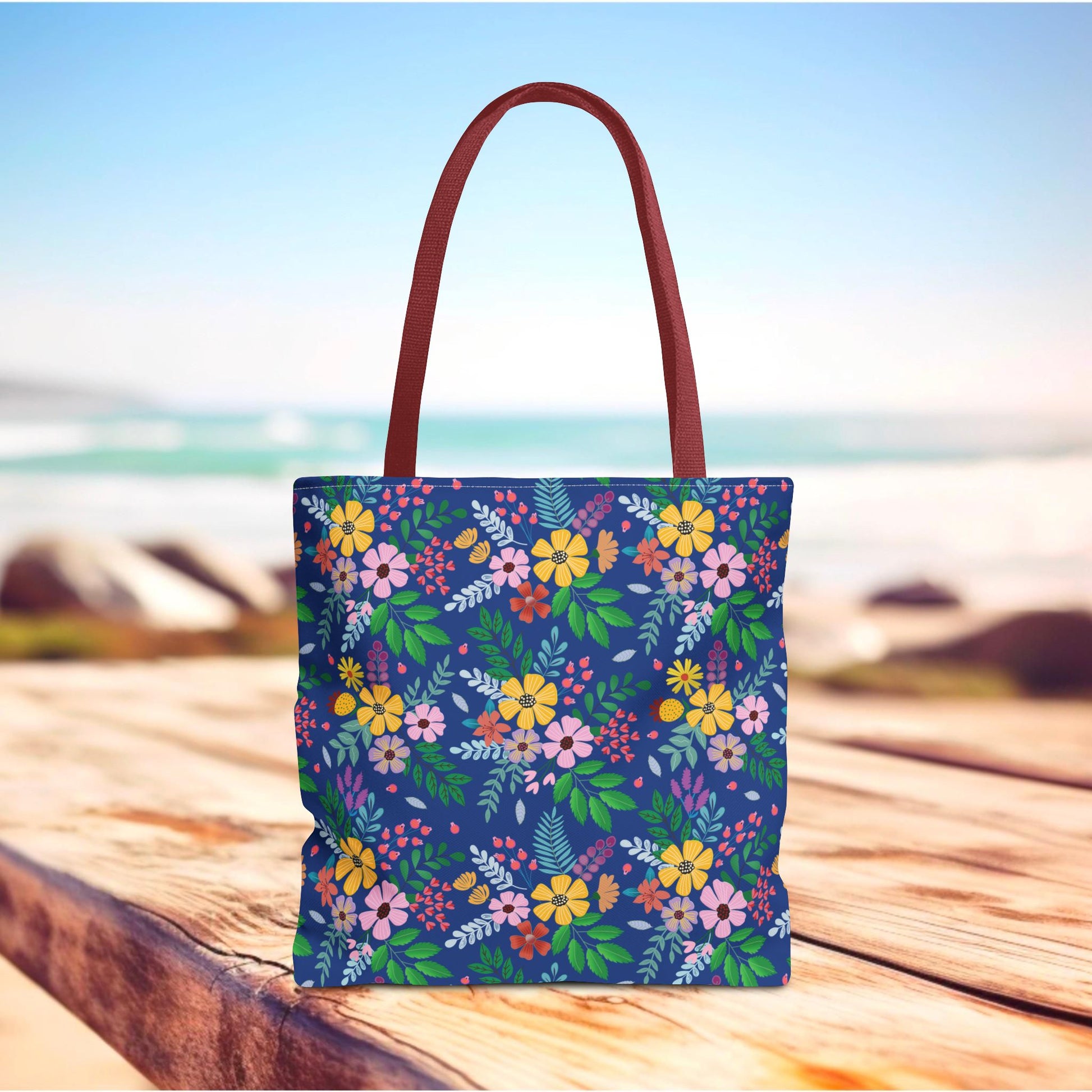 Deep Sea Floral Patch Tote Bag with burgundy handles features a vibrant floral pattern on a navy background, ideal for summer outings, embodying FireBrook Designs' uplifting and joyful aesthetic.