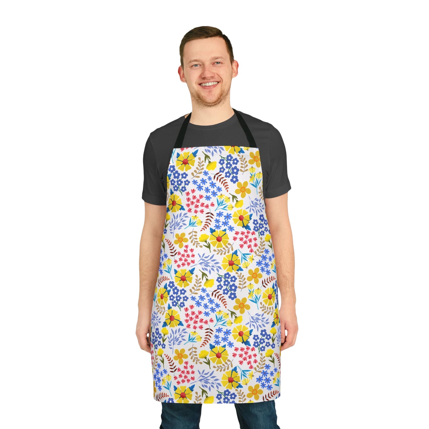 Apron Floral Design features a smiling man wearing a knee-length apron adorned with a vibrant floral print over a dark T-shirt and jeans, embodying FireBrook Essentials' stylish, joyful approach.