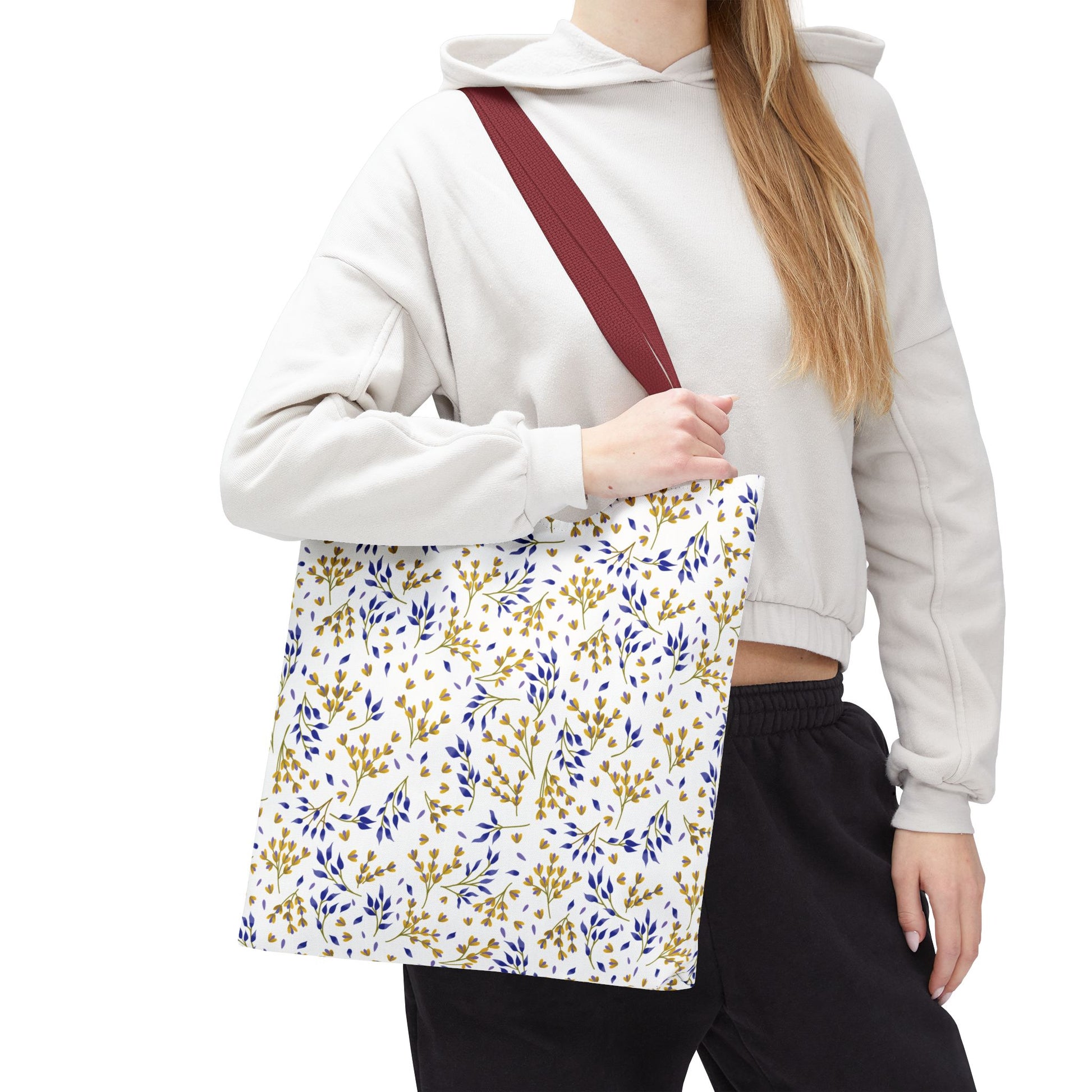 Wild Herb Garden Tote Bag carried by a person in casual attire. Featuring a cheerful yellow-gold and blue leafy pattern, burgundy strap, ideal for vibrant summer outings and practical everyday use.