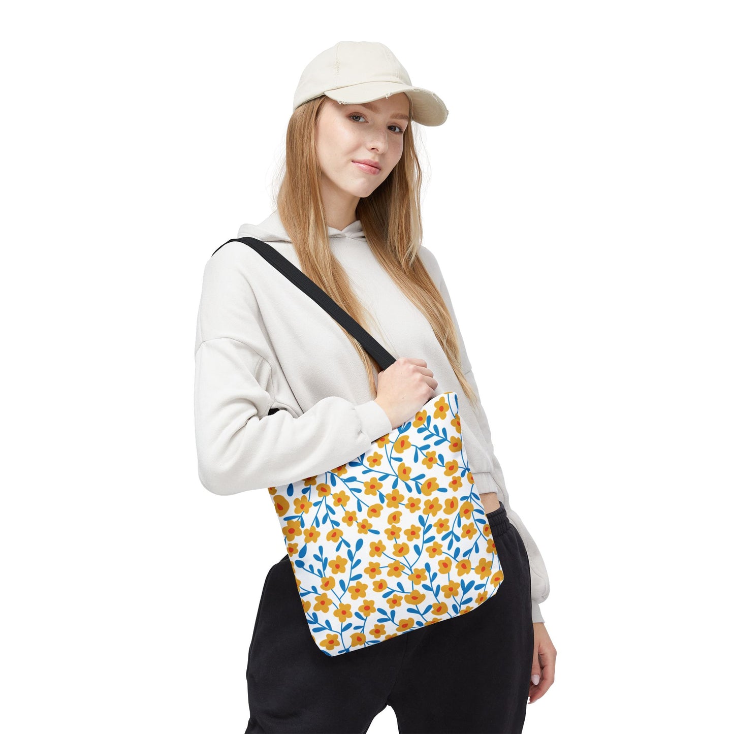 Floral Tote Bag modeled by a young woman, showcasing its cheerful yellow-orange flower pattern with blue stems, perfect for summer outings. The bag exudes FireBrook Designs' essence of style and positivity.