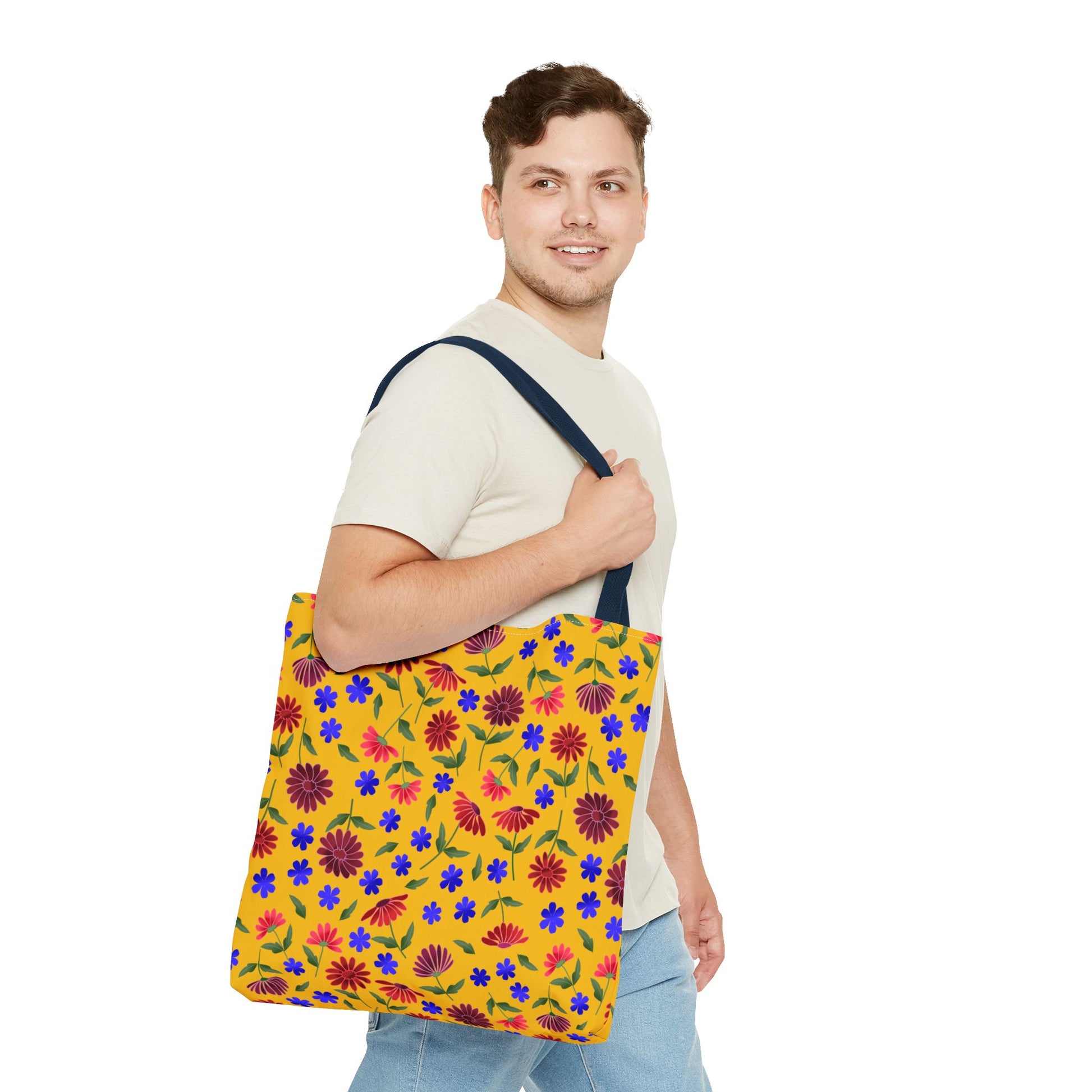 Golden Wildflower Tote Bag with a bright yellow floral pattern, navy-blue straps, and a large capacity, carried by a casually dressed young man, embodying FireBrook Designs' joyful, practical style.