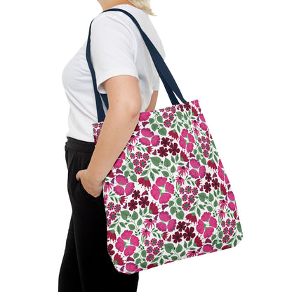 Person in a white T-shirt carrying the Pink Lady Tote Bag, featuring a floral print with pink and berry flowers, navy straps, embodying FireBrook Designs' cheerful and stylish essence.