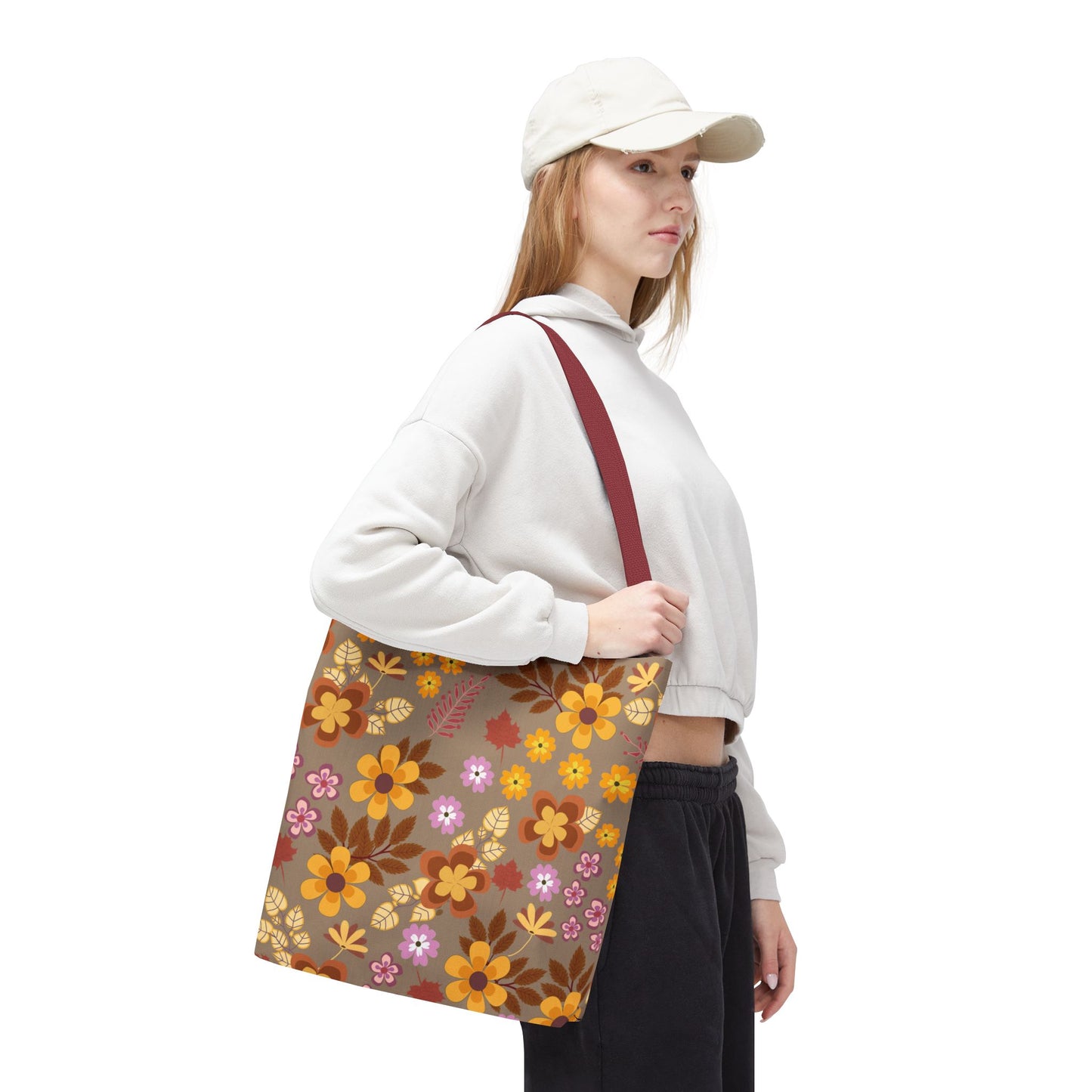 Person in casual attire carries the Harvest Brown Bloom Tote Bag, featuring a warm floral pattern in autumnal tones, ideal for cheerful summer outings. The tote complements FireBrook Designs' uplifting, stylish ethos.