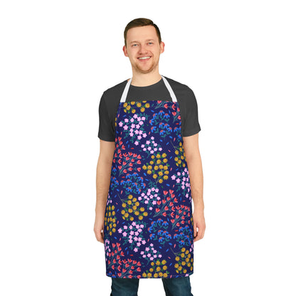 Man wearing a Floral Apron, featuring a vibrant pattern of pink, yellow, red, and blue flowers against a navy background. Perfect for cooking or crafting, this apron combines style and functionality.