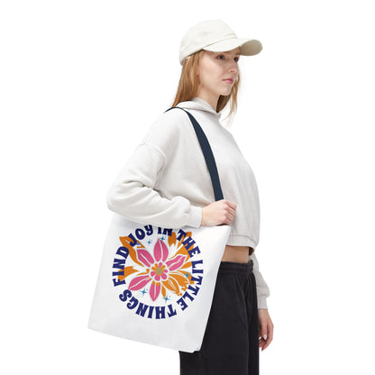 Woman in a white hat holding the Find Joy in Little Things tote bag, featuring a flower design, embodying positivity and versatile use from FireBrook Essentials.
