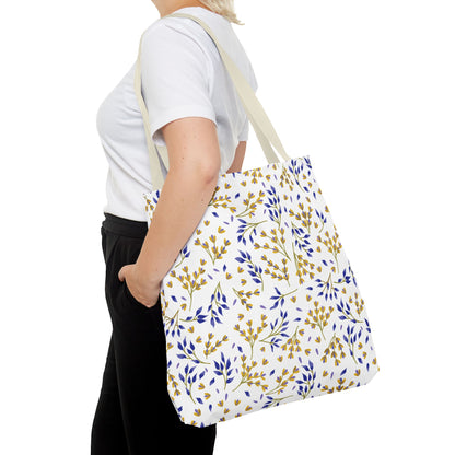 A person carries the Floral Tote Bag, featuring a white body with blue and golden-yellow botanical patterns, complemented by cream straps, exemplifying FireBrook Designs' cheerful and stylish aesthetic.
