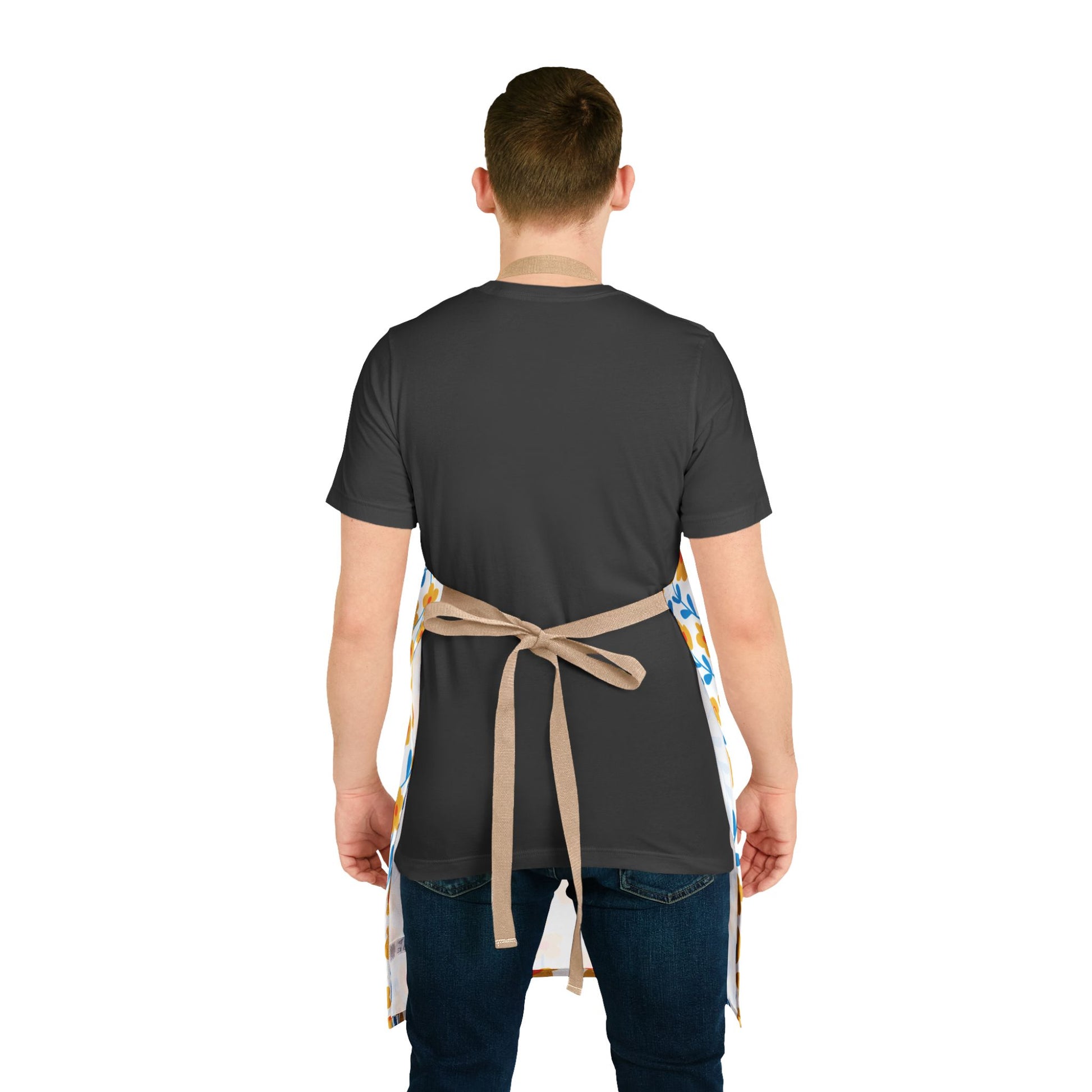 Floral Apron: A person wears a dark charcoal-gray T-shirt and blue jeans, showcasing a light-colored apron with vibrant blue and yellow motifs, tied at the back, emphasizing comfort and style.