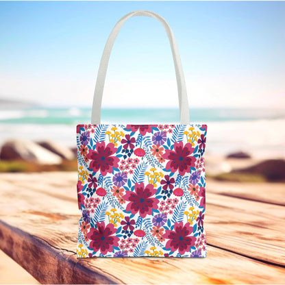 Violet Daisy Carnival Tote Bag on a wooden table, featuring vibrant magenta, purple, and yellow floral patterns with blue-green leaves, ideal for summer outings, embodying FireBrook Essentials' joyful and uplifting style.