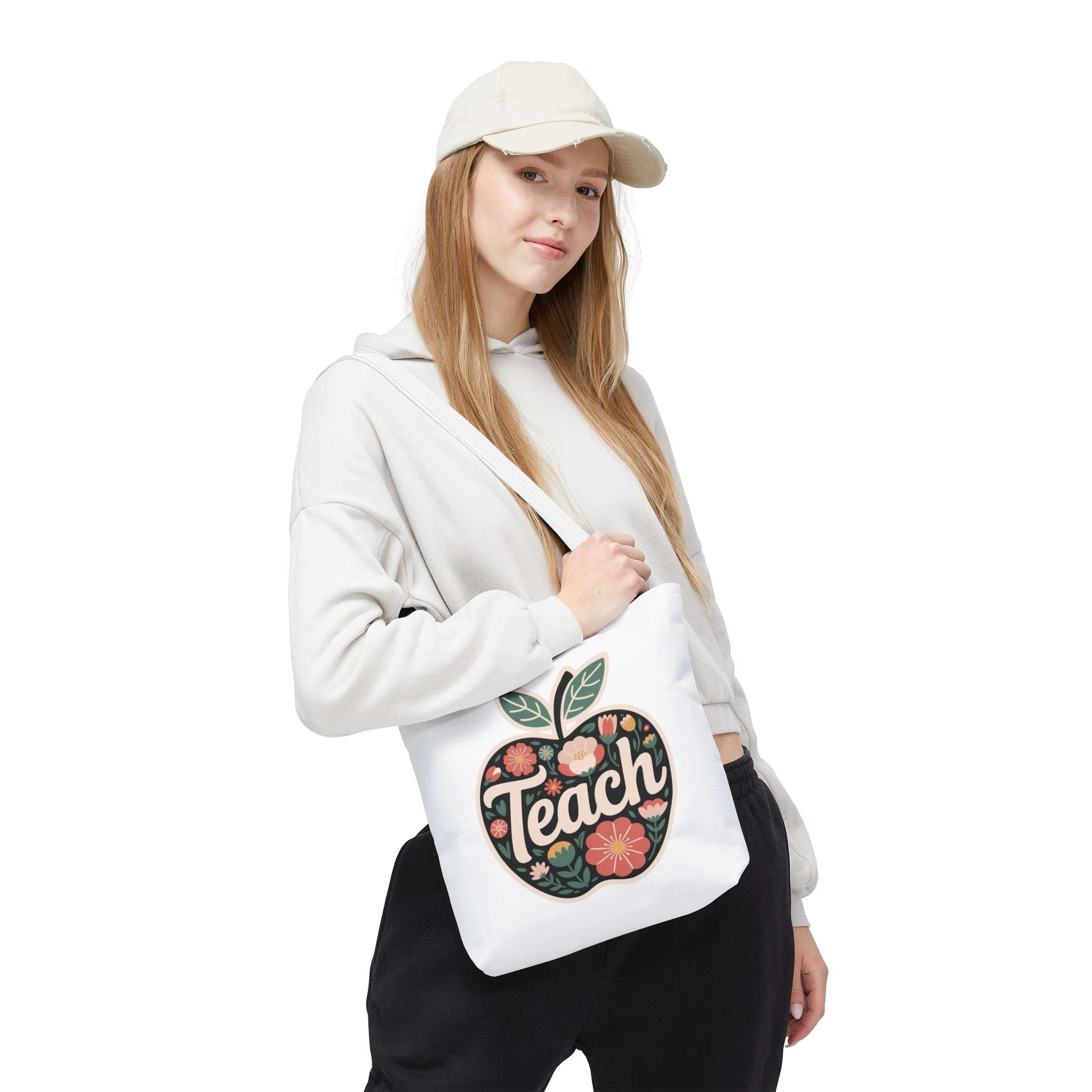 Floral Apple Tote Bag features a hand-drawn, pastel-colored apple design with 'TEACH' text, ideal for teachers. Durable 100% polyester with reinforced handles, available in various sizes from FireBrook Essentials.