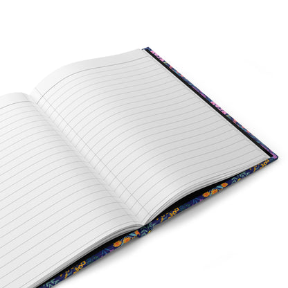 HARDCOVER JOURNAL, MATTE, RULED, 5X7, SEWN BIND, CLEAN-TEAR PAGES - FLORAL MEADOWS features open pages with ruled lines, set against a vibrant floral-patterned cover on a white surface.