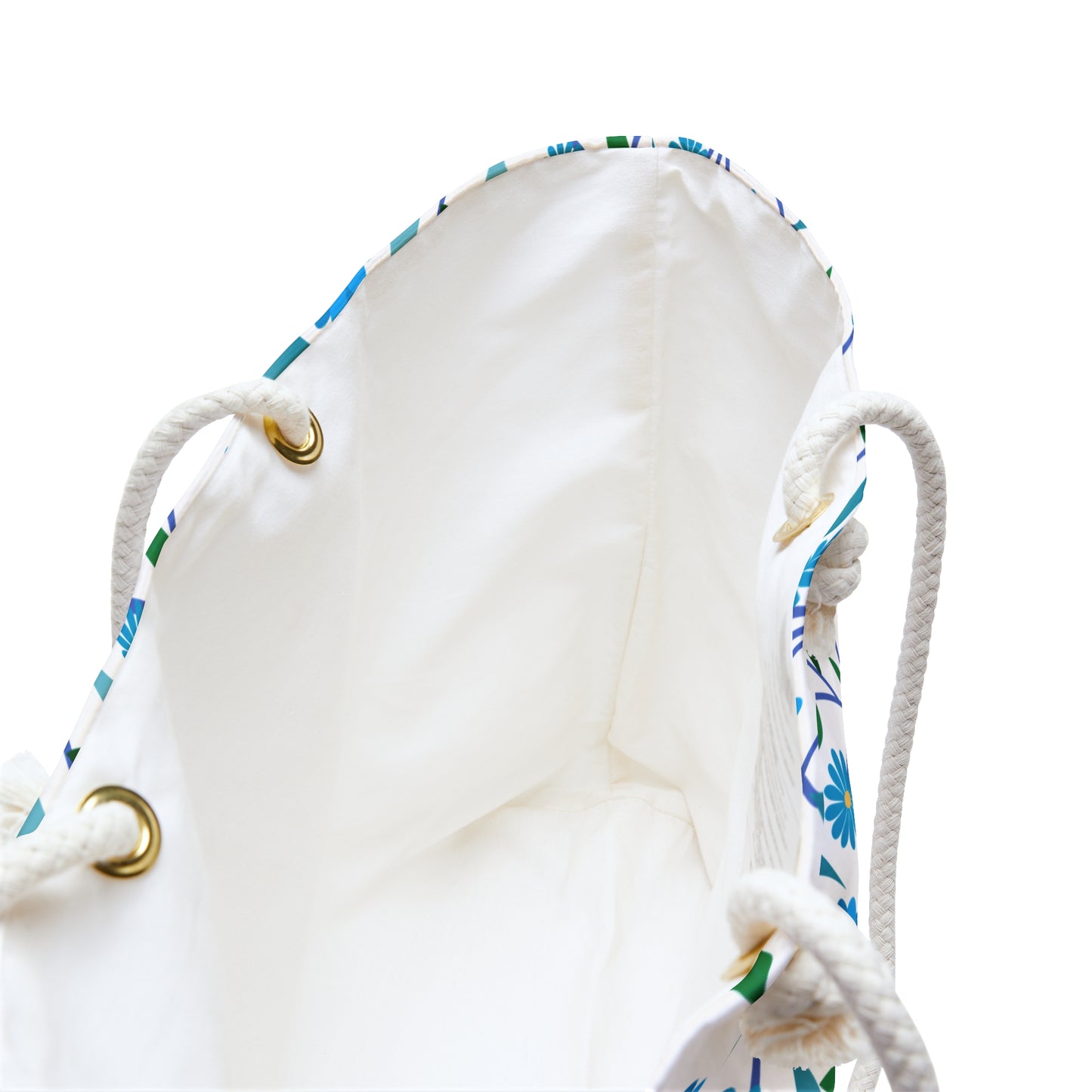 Weekender Bag with a white interior, brass grommets, and thick rope handles. A hint of blue-and-green floral pattern suggests a vibrant exterior, perfect for stylish weekend getaways.