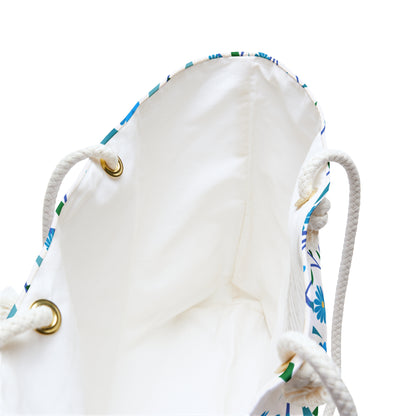 Weekender Bag with a white interior, brass grommets, and thick rope handles. A hint of blue-and-green floral pattern suggests a vibrant exterior, perfect for stylish weekend getaways.