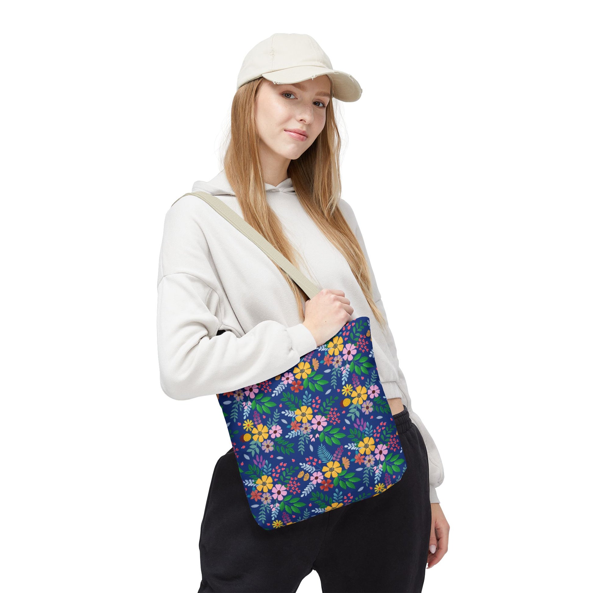 Floral Tote Bag carried by a young woman, featuring a vibrant floral pattern with yellow, pink, and orange blooms on deep blue. Perfect for joyful summer outings, embodying FireBrook Essentials' uplifting design ethos.