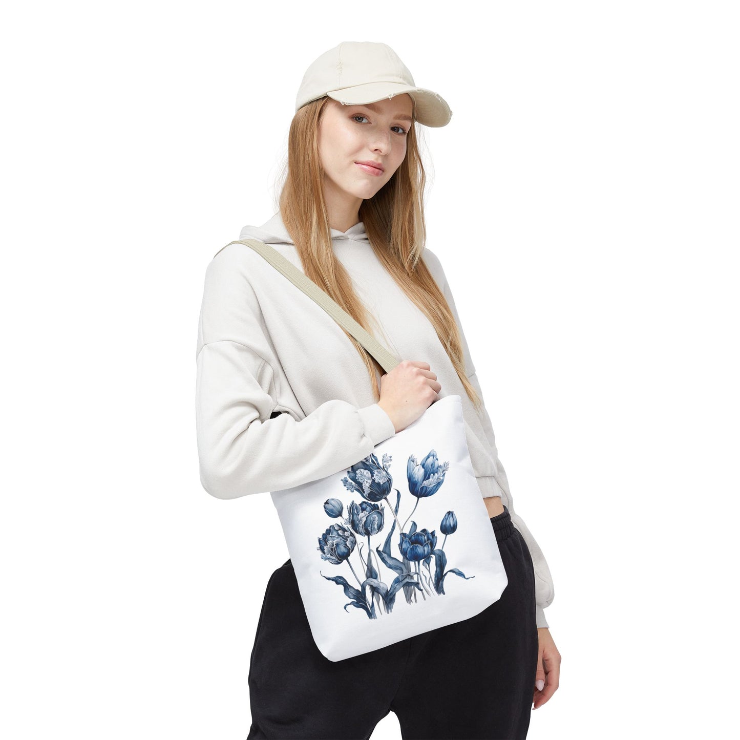 Woman wearing a hat holds Flowers in Blue Hue Watercolor Tote Bag, showcasing its floral design and stylish functionality.
