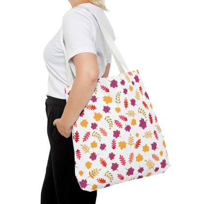 Autumn Leaves Tote Bag featuring a scattered-leaf pattern in autumnal hues, worn over the shoulder of a person in casual attire. The bag's sturdy design is ideal for daily essentials.
