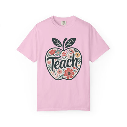 Floral Apple TEACH T-shirt: Unisex garment-dyed tee with a large apple filled with pastel floral art, overlaid with TEACH in textured script, embodying a whimsical, artistic vibe. Ideal for educators.