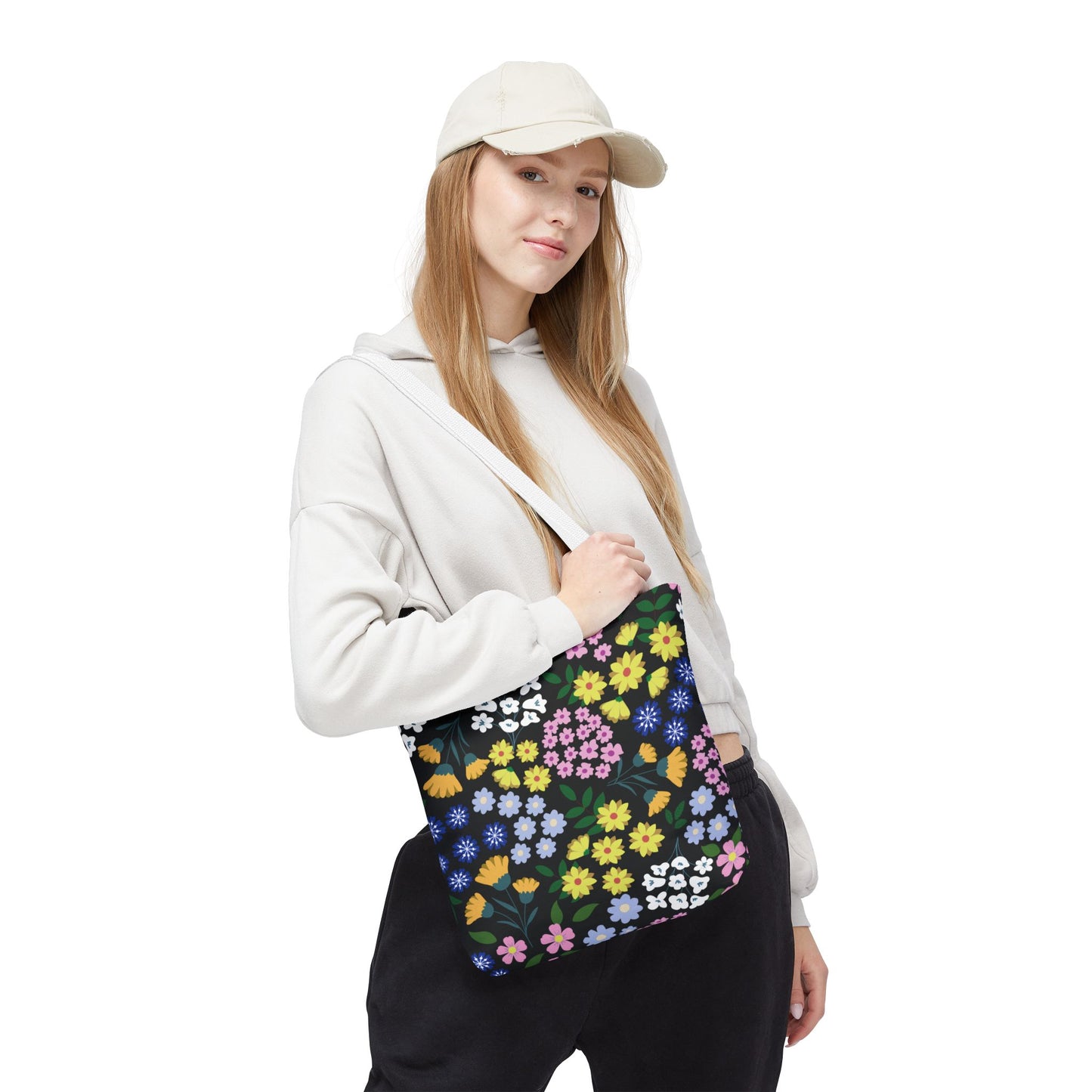 A young woman wears a light hoodie and cap while carrying the Floral Tote Bag, featuring a vibrant floral pattern, ideal for joyful summer outings.