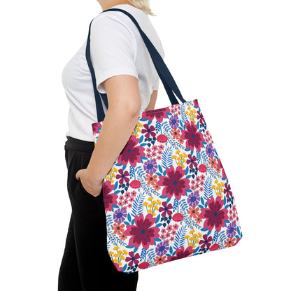 Person wearing a white T-shirt and black pants carries the Violet Daisy Carnival Tote Bag, featuring bright floral print with navy straps, perfect for joyful summer outings.