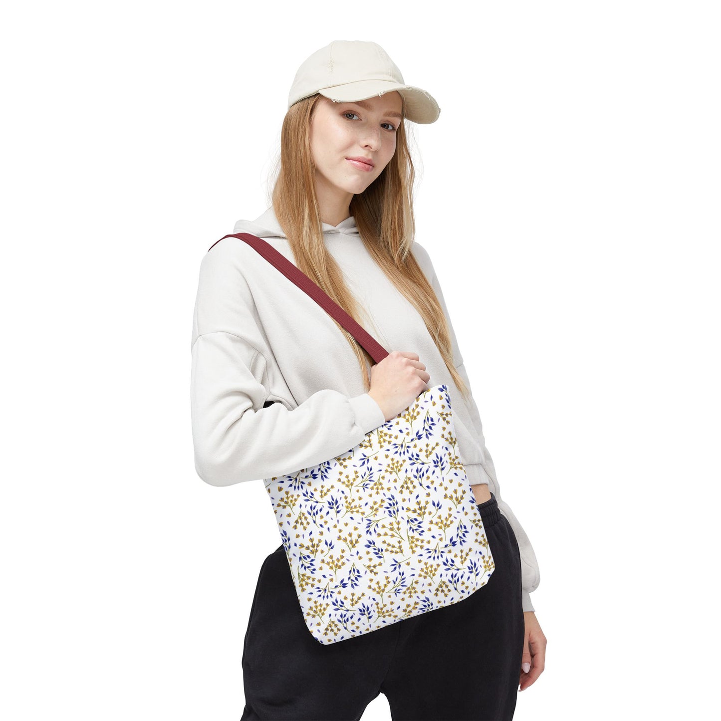Person models the Wild Herb Garden Tote Bag, featuring a blue-and-gold leaf pattern on a white canvas with a burgundy strap, embodying FireBrook Designs' vibrant, joyful style.