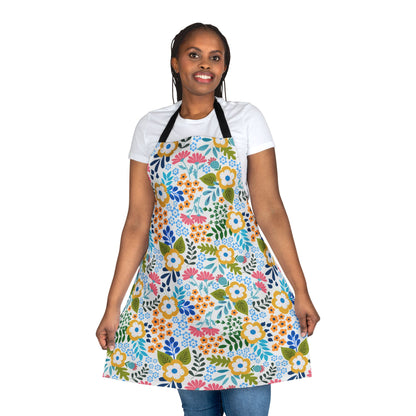 Floral Apron: A smiling woman models a knee-length apron with a vibrant floral pattern over a white T-shirt and blue jeans, showcasing its comfortable, stylish design from FireBrook Essentials.