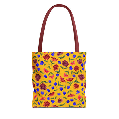 Golden Wildflower Tote Bag: A vibrant canvas tote with a bright yellow background and floral print of red daisies and blue blossoms, featuring sturdy black handles and reinforced stitching for durability.