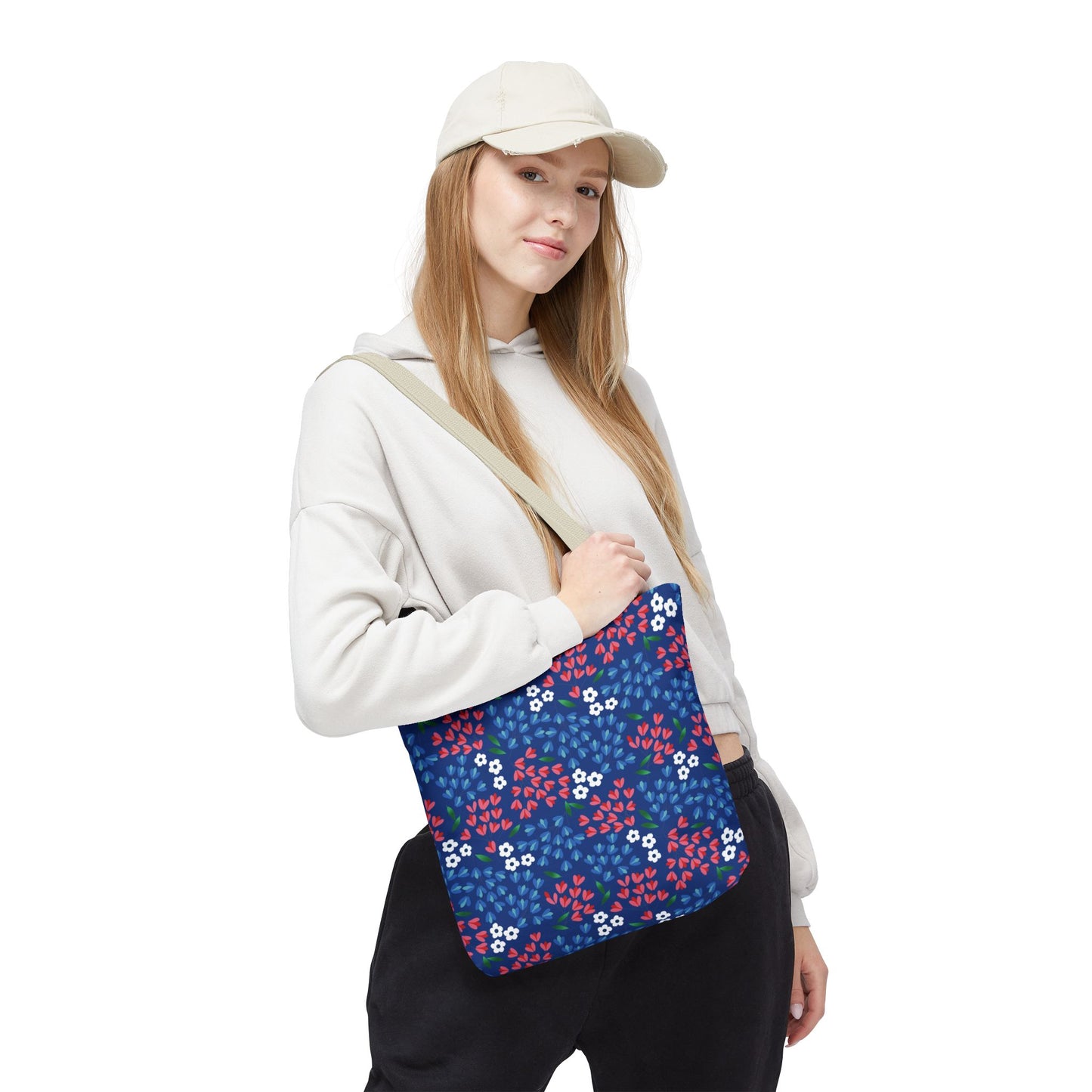 Floral Tote Bag featuring a navy-blue background with red leaves, tiny white blooms, and green accents, worn by a casually dressed woman, exemplifying FireBrook Essentials' blend of style and practicality.