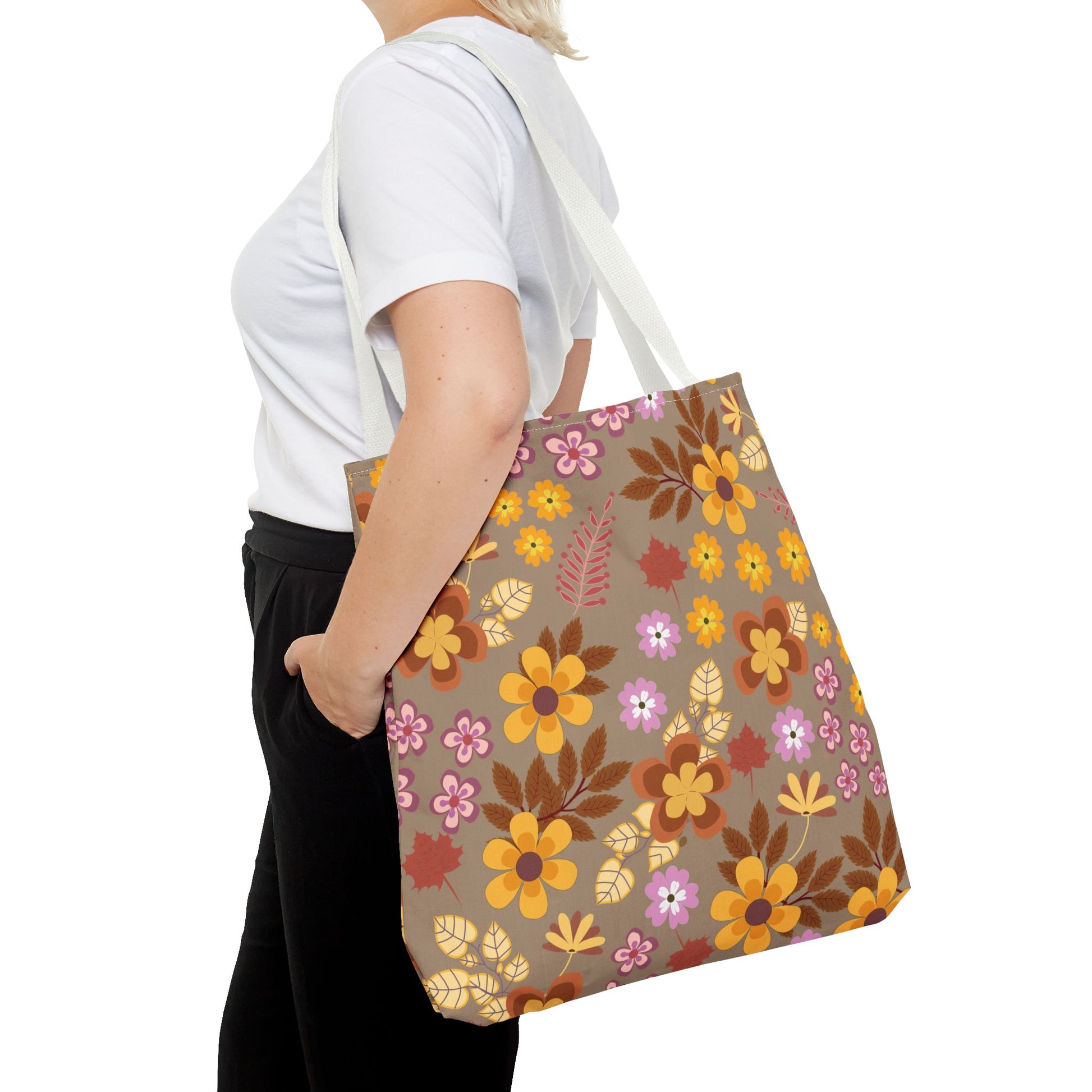 Harvest Brown Bloom Tote Bag with large gold, orange, brown, and dusty pink floral pattern carried over a shoulder. Ideal for summer outings, boasting durable polyester and reinforced handles for strength.