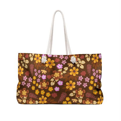 Weekender Bag with thick white rope handles, showcasing a vibrant floral pattern in brown, orange, yellow, and pink, ideal for stylish travel. Designed by FireBrook Designs for joyful, easygoing adventures.