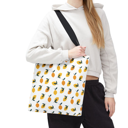 Person wearing a light-colored hoodie and dark pants carries the Lemon Drop Toss Tote Bag, featuring vibrant yellow/orange lemons with green leaves, perfect for adding cheer to everyday style.