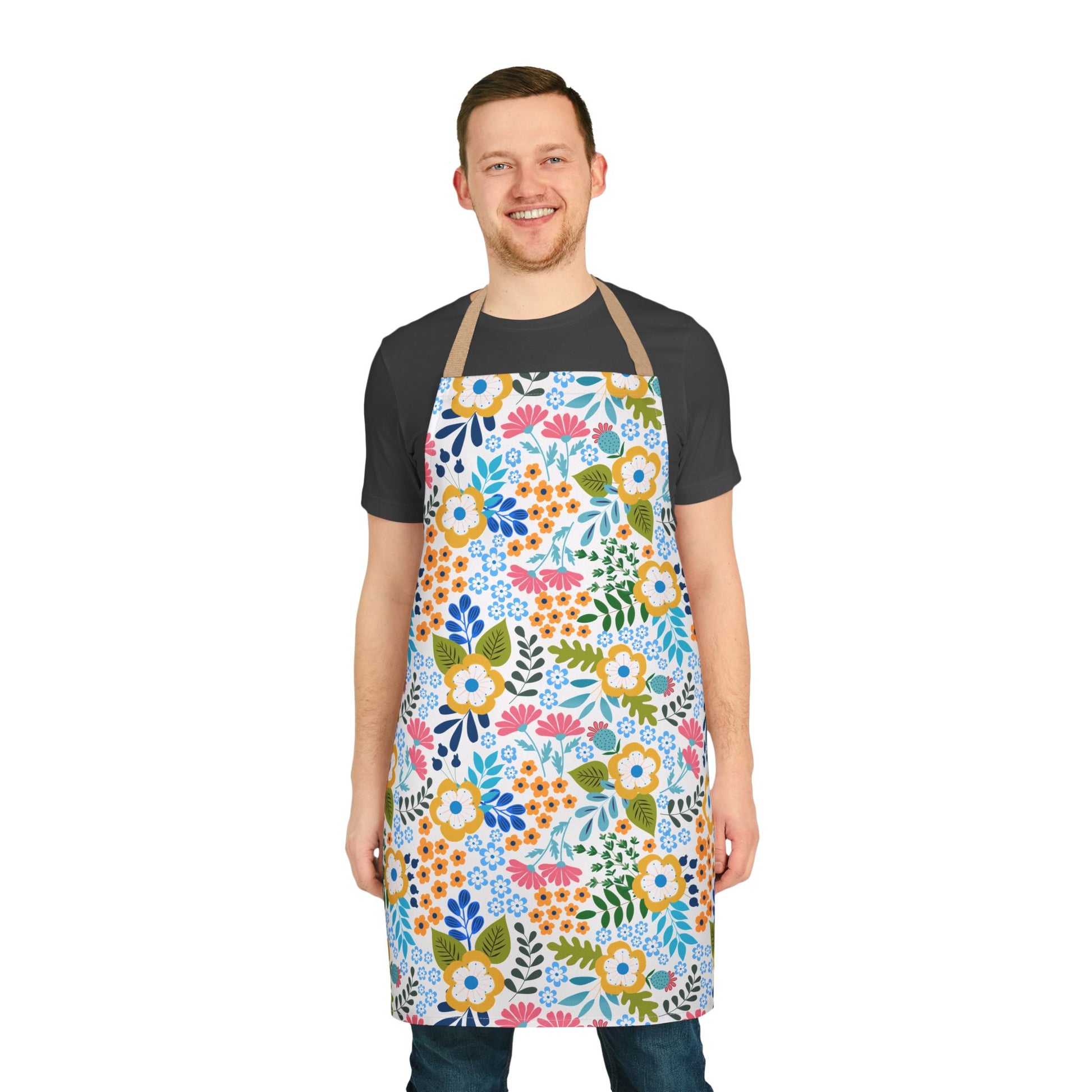 A man models the Floral Apron from FireBrook Designs, featuring a vibrant floral pattern and beige straps. Crafted from 100% polyester canvas, it offers comfort and stain-free protection for various activities.