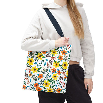 A person models the Sunny Meadow Mix Tote Bag, showcasing its vibrant floral pattern in yellows and oranges, complemented by a navy strap, ideal for cheerful summer outings.