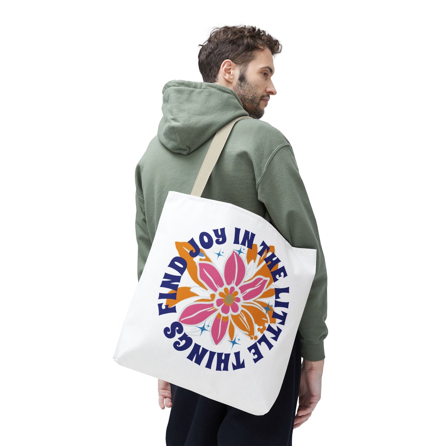 Man wearing green sweatshirt, carrying a Find Joy in Little Things tote bag with a floral design, promoting positivity and everyday practicality.