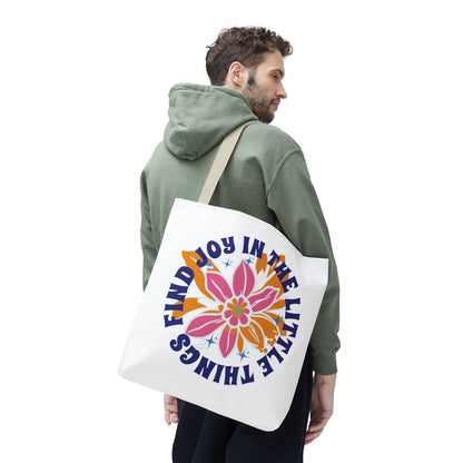 Man wearing green sweatshirt, carrying a Find Joy in Little Things tote bag with a floral design, promoting positivity and everyday practicality.