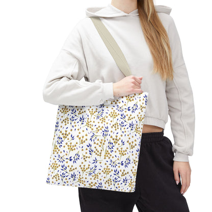 Wild Herb Garden Tote Bag with blue and golden-yellow leafy sprigs, carried by a person in a beige hoodie. Ideal for summer outings with durable polyester build and textured beige strap.