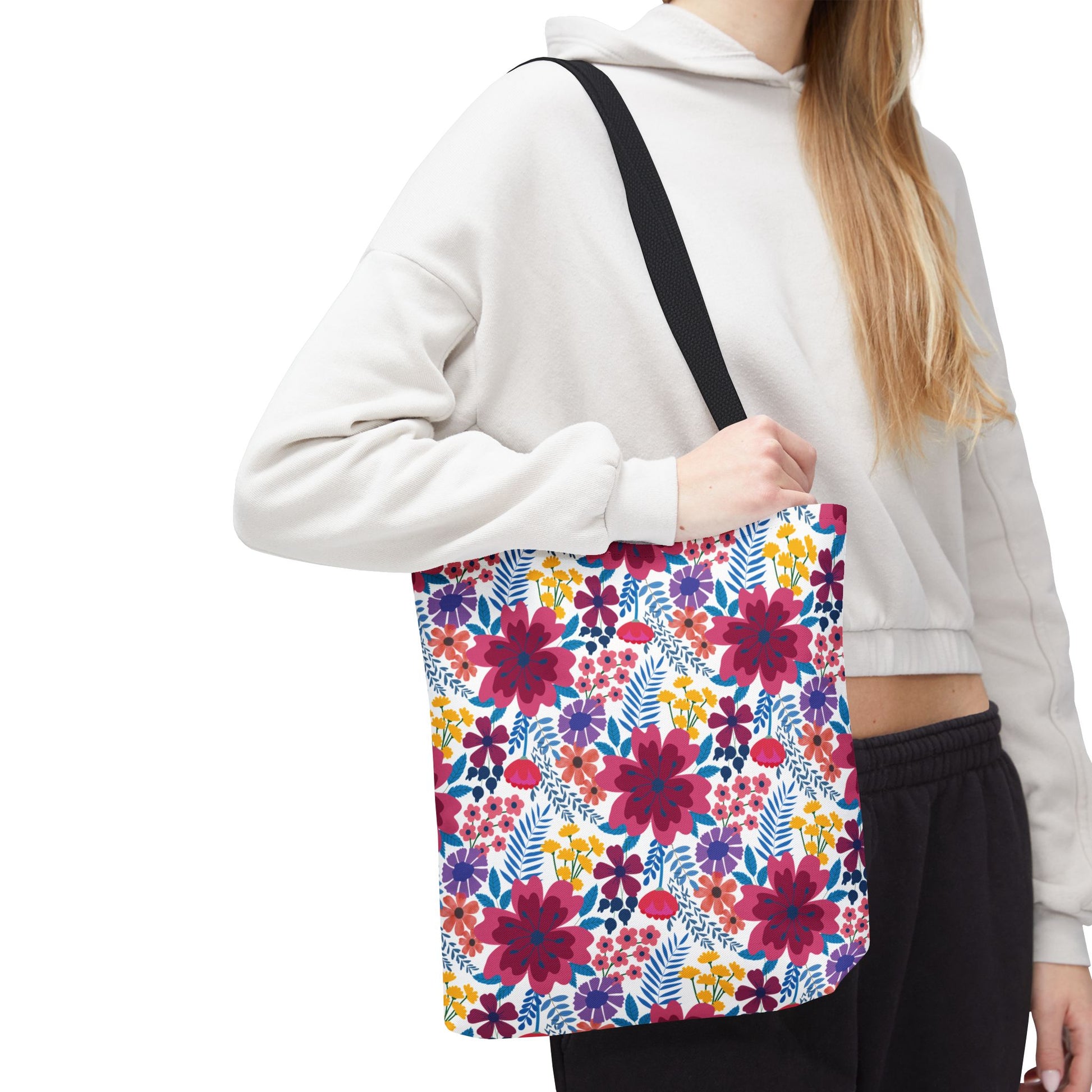 Violet Daisy Carnival Tote Bag featuring bold magenta, purple, orange, and yellow floral pattern with blue foliage on white. Ideal for summer outings, it embodies FireBrook Designs' uplifting and stylish essence.