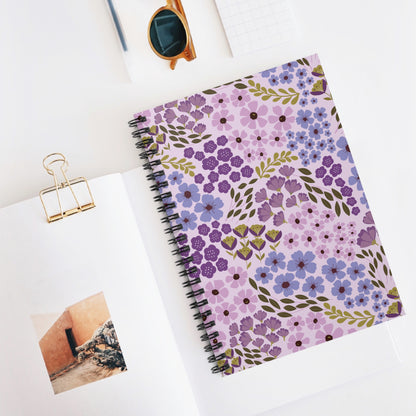 Floral Spiral Notebook with purple and lilac flower pattern, central on a white desk. Nearby, a gold binder clip and sunglasses add stylish accents, reflecting FireBrook Designs' uplifting, creative ethos.