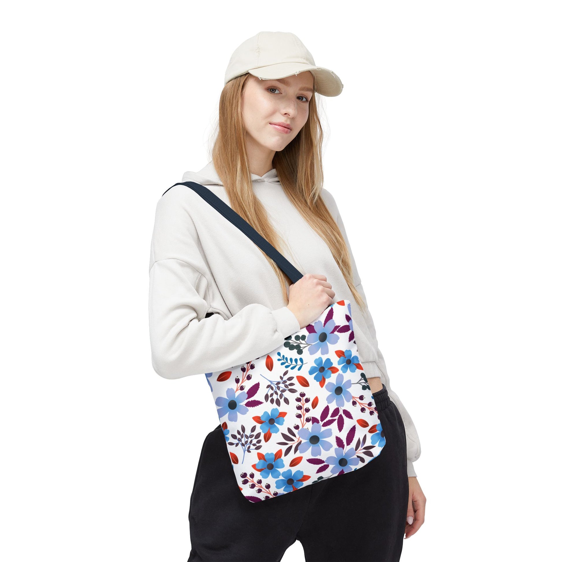 Floral Tote Bag slung over a woman's shoulder, featuring a vibrant pattern of blue, purple, and red flowers on a durable canvas. Perfect for stylish, casual outings, embodying FireBrook Designs' uplifting aesthetic.