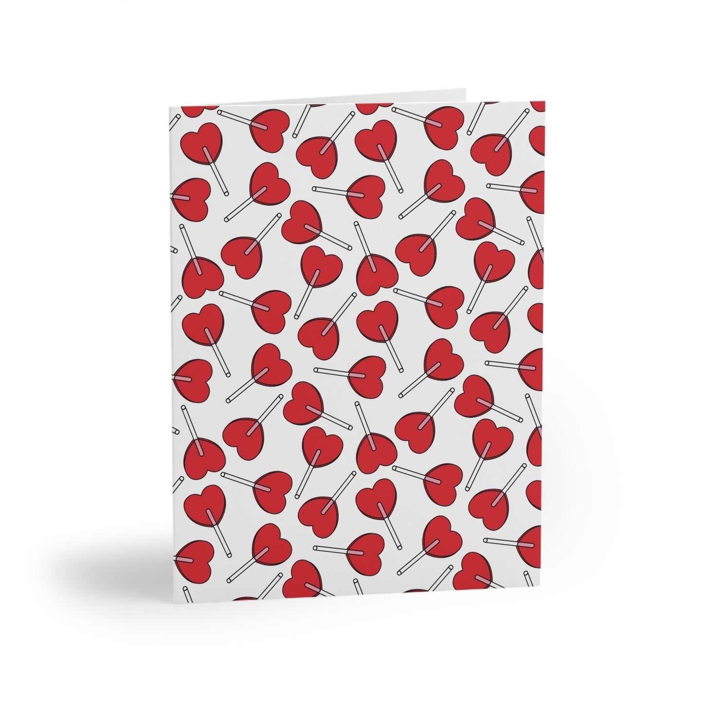 Love Greeting Cards — Pack of 8/16/24, featuring a folded card with a charming pattern of red heart-shaped lollipops on a white background, embodying FireBrook Designs' uplifting and joyful essence.