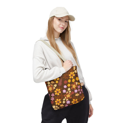 Young woman wearing a light-beige baseball cap and off-white hoodie showcases a Floral Tote Bag with warm autumn tones, perfect for joyful summer outings, embodying FireBrook Designs' uplifting style.