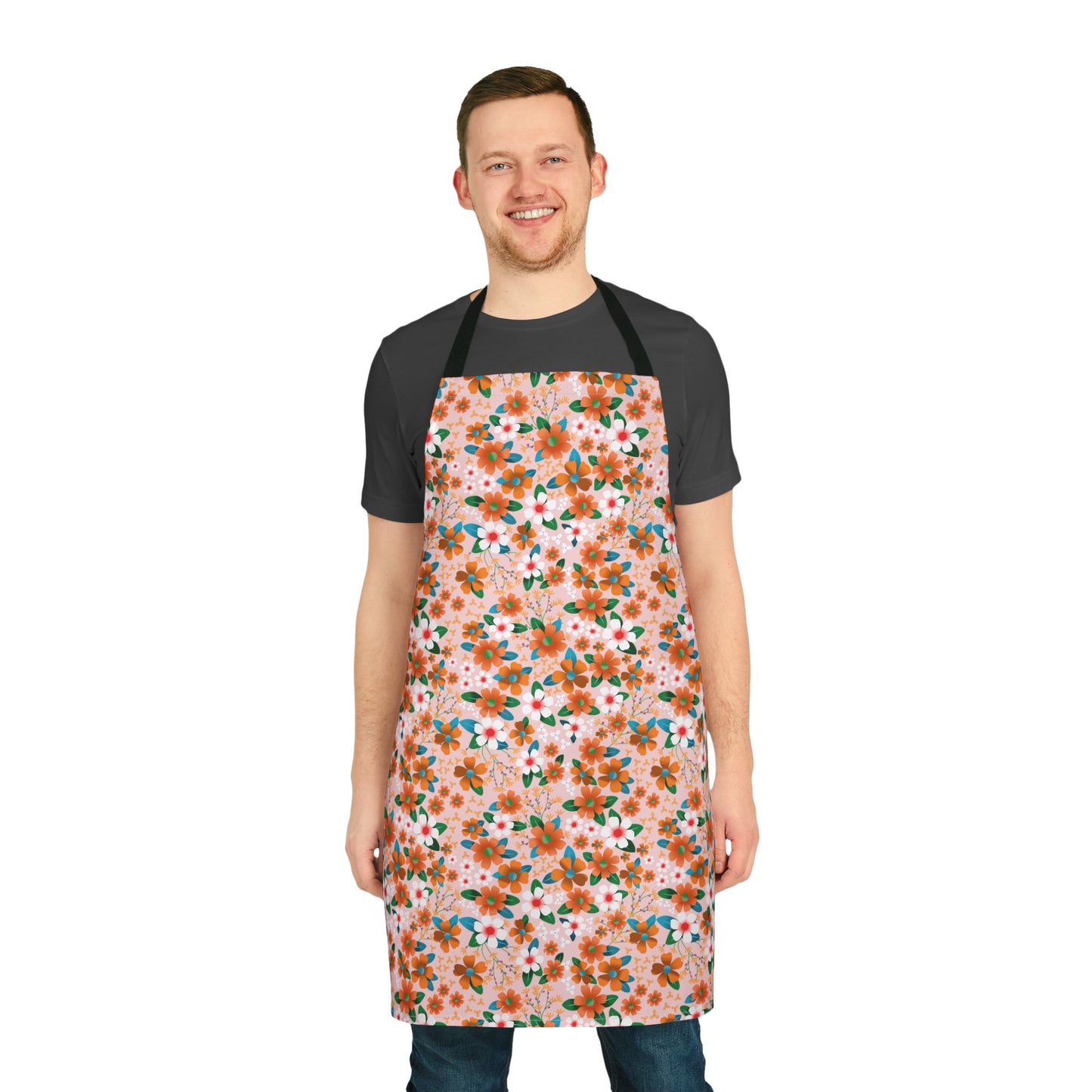 Smiling man models the Floral Apron, featuring orange and white blossoms with green leaves on light pink. This stylish, stain-free apron from FireBrook Designs offers comfort and vibrant, uplifting design.