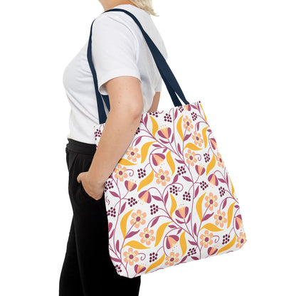 Model displaying the Floral Tote Bag with a vibrant floral-and-leaf design, perfect for summer. The tote features durable polyester, reinforced navy handles, and boxed corners for extra space.