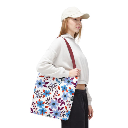 Person in profile wearing a cream hoodie, dark pants, and a light-beige cap, showcasing the Floral Tote Bag with a vibrant blue, purple, and red floral pattern, ideal for joyful summer outings.