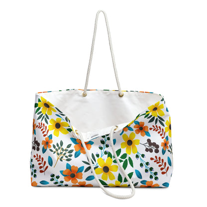 Weekender Bag featuring a bright floral pattern with yellow, orange, and teal blossoms, and sturdy white rope handles. Ideal for stylish trips, this spacious tote has a plain white interior.