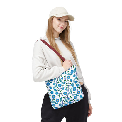 Blue Floral Tote Bag with small blue flowers and green leaves on a white background, featuring a contrasting burgundy strap, perfect for summer outings, offering durability and stylish practicality for daily use.