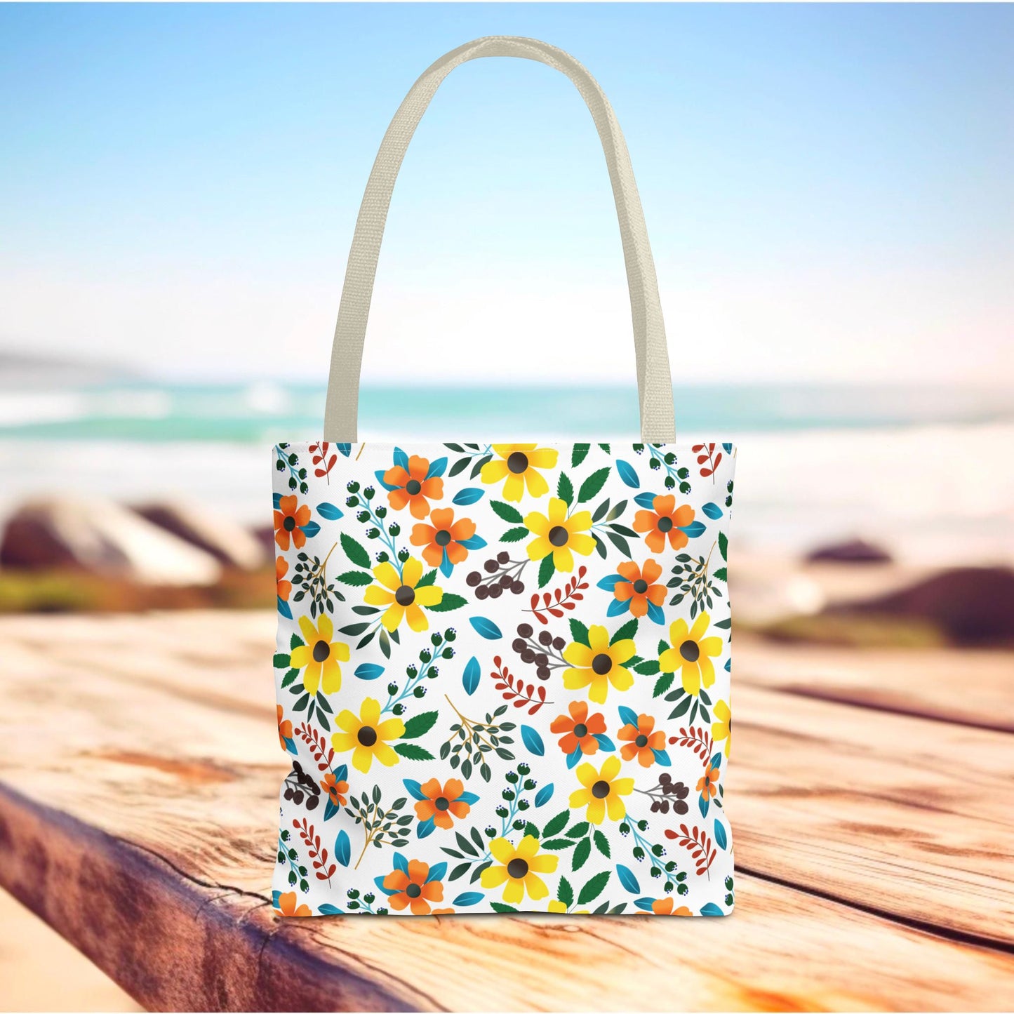 Sunny Meadow Mix Tote Bag on a wooden surface, adorned with vibrant yellow and orange floral patterns, ideal for summer outings, reflecting FireBrook Designs’ cheerful and stylish approach to everyday accessories.
