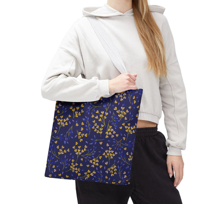 Floral Tote Bag featuring a navy base with a gold-yellow and deep blue sprig pattern, carried by a person in a light hoodie, exemplifying FireBrook Designs' cheerful, uplifting style.