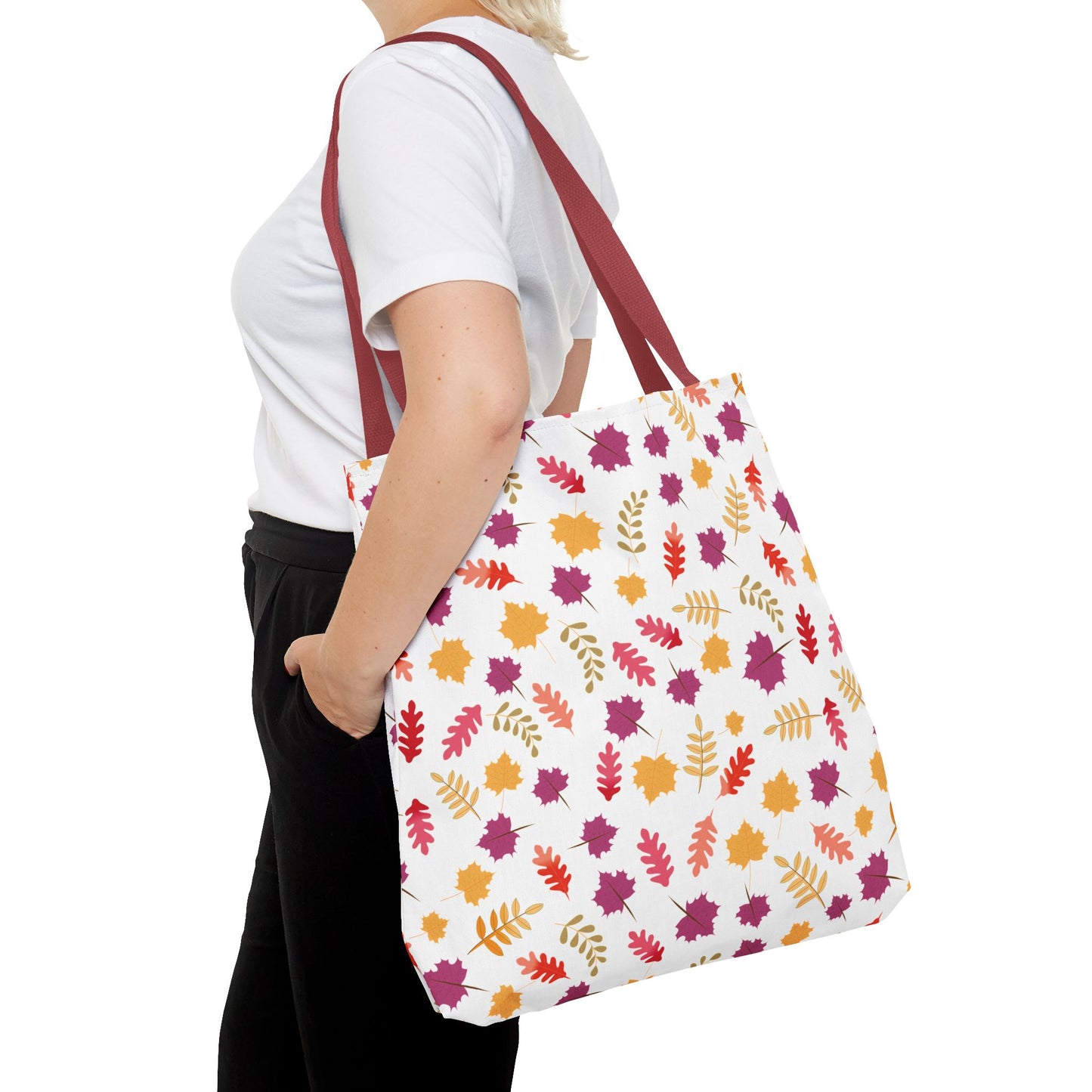 Person carrying the Autumn Leaves Tote Bag, featuring a vibrant leaf pattern and burgundy straps, ideal for everyday use with reinforced stitching and boxed corners for extra durability.
