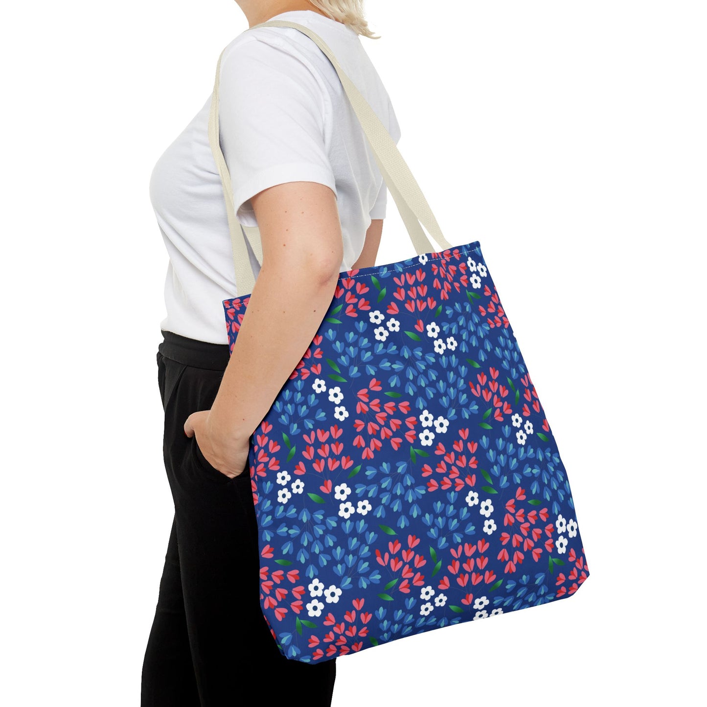 Person wearing a plain white T-shirt carries the Berry Blue Festival Tote Bag, featuring vibrant floral patterns on a deep blue background, ideal for cheerful, stylish outings.