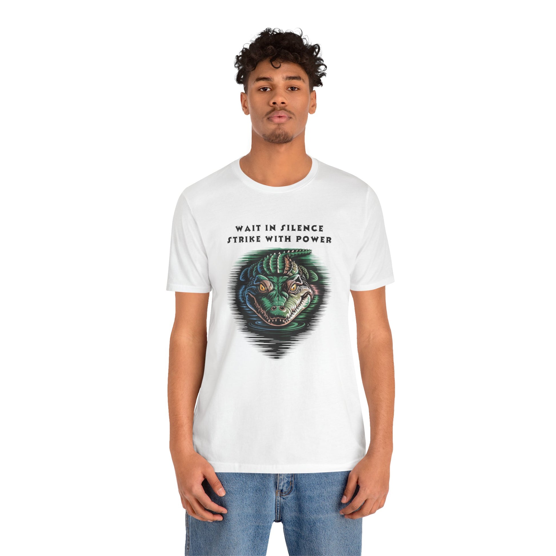Crocodile: Walk in Silence, Strike with Purpose Bella+Canvas Unisex T-Shirt featuring a bold cartoon crocodile face design, worn by a man in jeans, embodying stealth and determination.